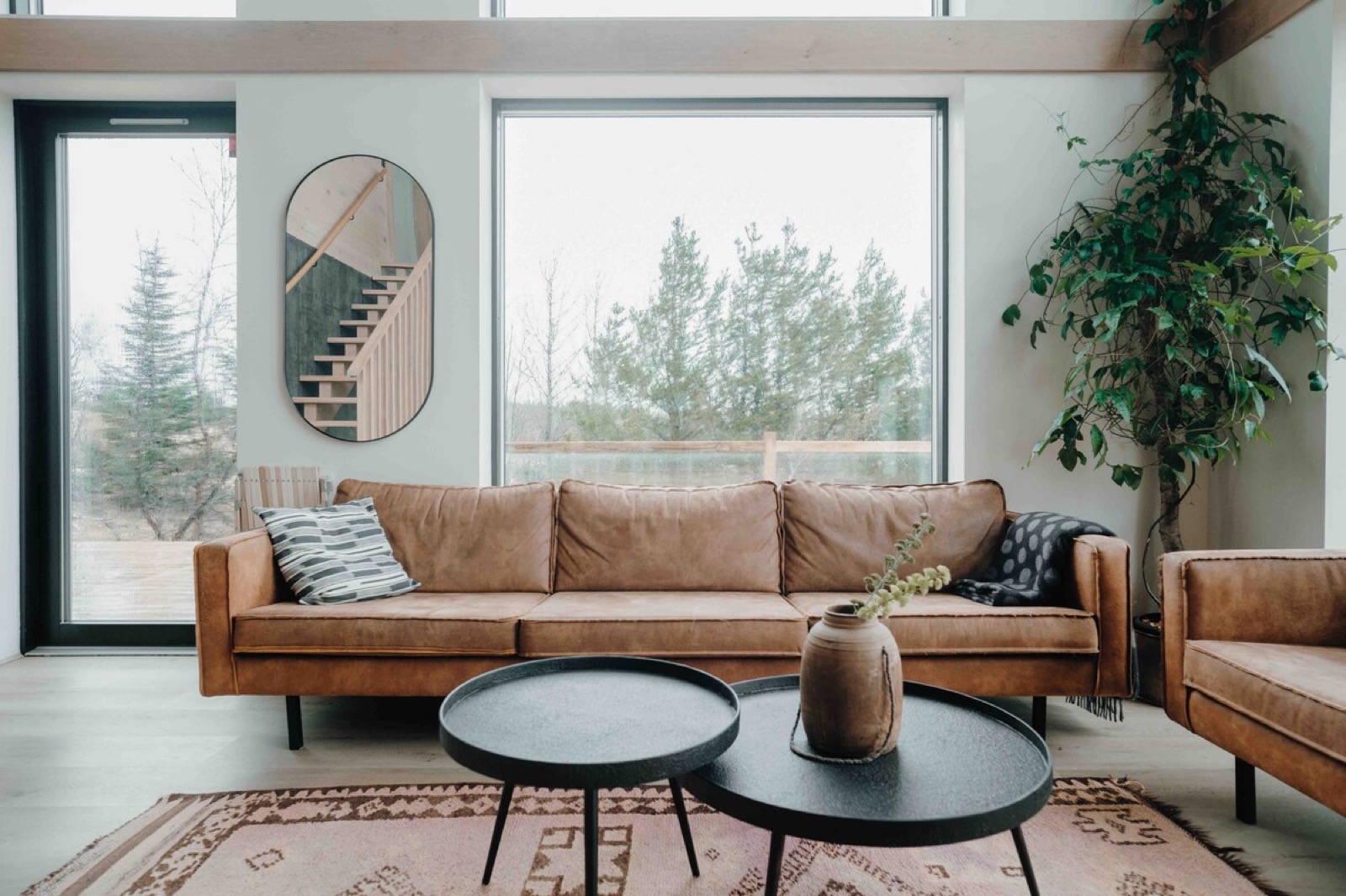 Tan leather sofas, a patterned rug and low black tables in the tall living room